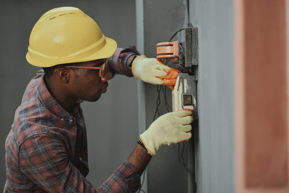 Electrician in a hard hat wiring an outdoor electrical panel