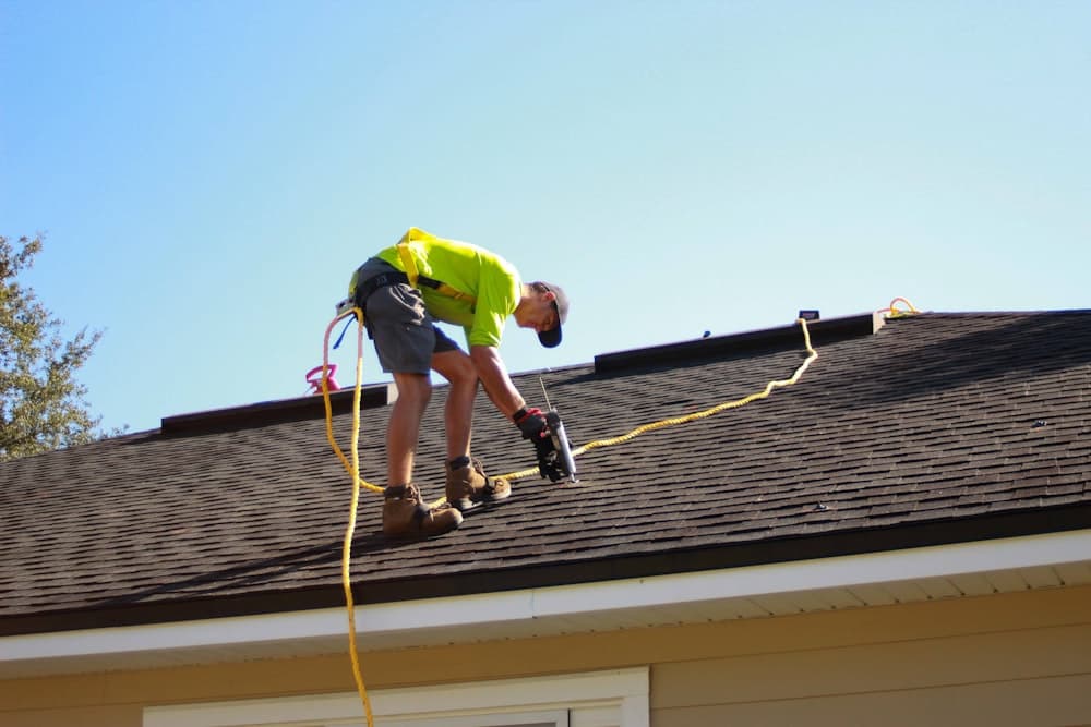 Roofer working on the shingles of a residential roof on a clear day